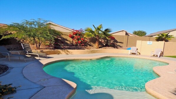 Relax by the pool surrounded by lush greenery and comfortable lounge chairs.