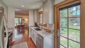Una cocina moderna con comedor, armarios de madera y un amplio ventanal.