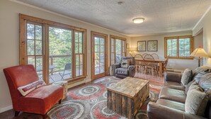 Amplia sala de estar con ventanas grandes, chimenea, zona de comedor y un rincón de descanso acogedor.