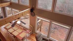 A high-ceilinged room with large windows, a wooden dining table, and a cozy seating area. - Unwind with Sautee Start Line, Hot tub, Firepit, Hammock, PS3 (Clarkesville)