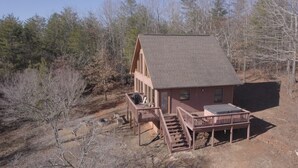 A cabin with a deck and a hot tub, surrounded by trees. - Unwind with Sautee Start Line, Hot tub, Firepit, Hammock, PS3 (Clarkesville)