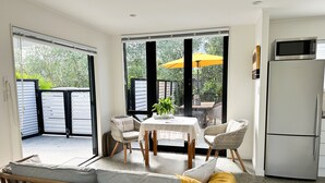 A modern kitchen with a refrigerator, a dining area with a table and chairs, and a view through large glass doors to an outdoor patio. - Black & White Retreat
 (Omaha Beach)