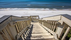 Ein hölzerner Steg führt zu einem Strand mit freiem Blick auf das Meer.
