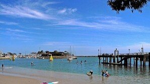 Uma praia com um cais, águas calmas e barcos.