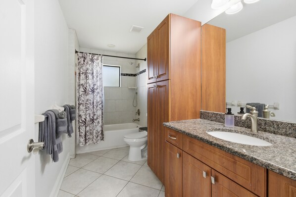 A bathroom with a wooden vanity, a sink, and a shower area.