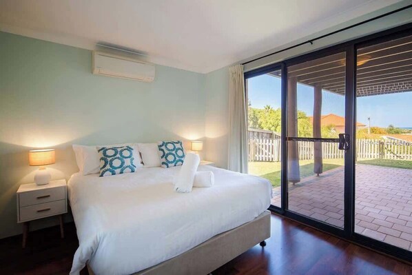 A bedroom with a large bed, a nightstand, a sliding glass door leading to an outdoor area.