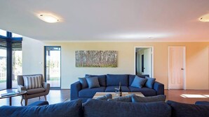 A modern living room with a dark blue sectional sofa, a small table, and a painting on the wall.
