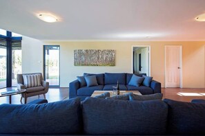 A modern living room with a dark blue sectional sofa, a small table, and a painting on the wall.