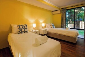 A hotel room with two beds, a large window, and a wooden floor.