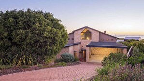 A modern house with a large window, a brick exterior, and a paved driveway.