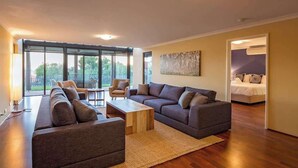 A modern living room with a sectional sofa, a coffee table, and a dining area.