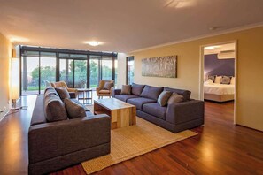 A modern living room with a sectional sofa, a coffee table, and a dining area.