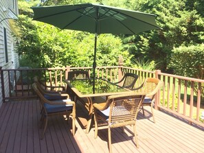 A wooden deck with wicker furniture and a green umbrella.