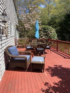 A wooden deck with wicker furniture and a blue umbrella.