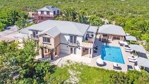 Una casa grande con piscina, varios balcones y un exuberante paisaje circundante.