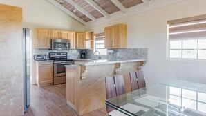 Una cocina moderna con armarios de madera, electrodomésticos de acero inoxidable y una mesa de comedor de vidrio.