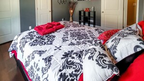 A bedroom with a large bed, a bedside table, a wall-mounted shelf, and a door. - 4BR Smart Luxe Condo w/ Pool View, Gated Community: close to Costco & Top Golf (McAllen)