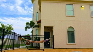 A building with a pool, a hammock, and a fenced area. - 4BR Smart Luxe Condo w/ Pool View, Gated Community: close to Costco & Top Golf (McAllen)