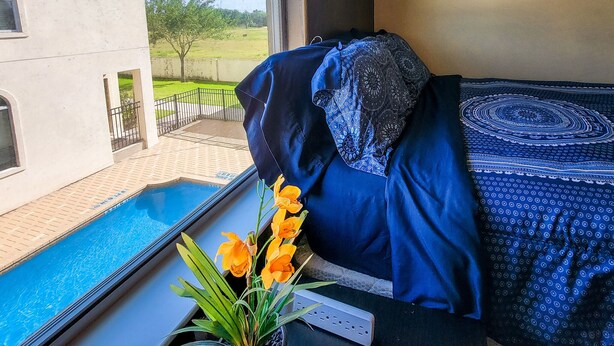 A bedroom with a view of a swimming pool and a house. - 4BR Smart Luxe Condo w/ Pool View, Gated Community: close to Costco & Top Golf (McAllen)