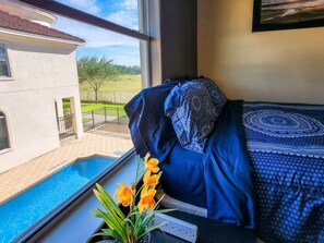 A bedroom with a view of a swimming pool and a house. - 4BR Smart Luxe Condo w/ Pool View, Gated Community: close to Costco & Top Golf (McAllen)