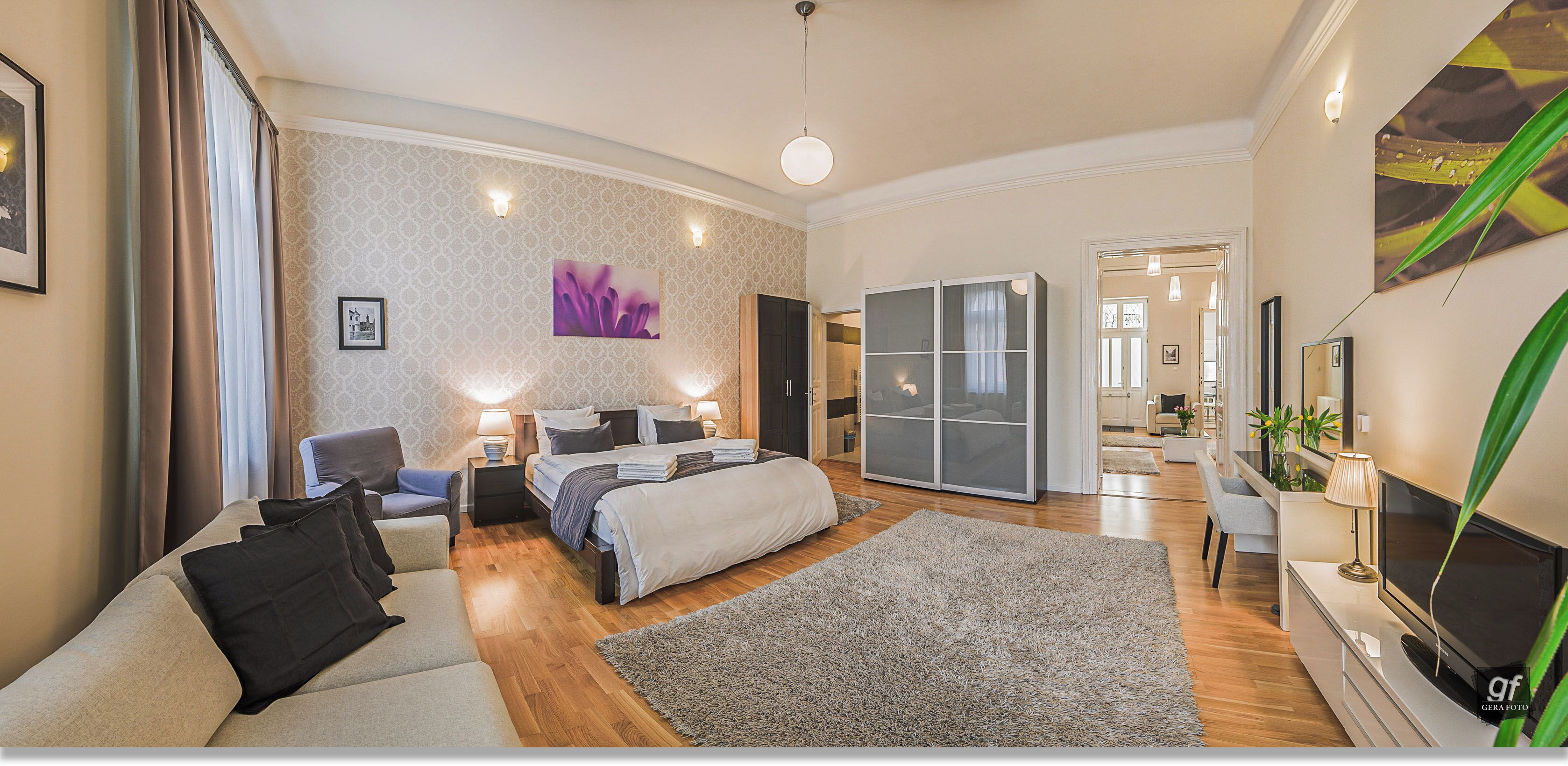 Et moderne hotelværelse med seng, sofa, fjernsyn og spiseplads.