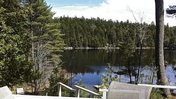 A lakeside deck with a glass table and chairs, overlooking a calm lake and dense forest. - Swim and Kayak at this freshwater location. Sleep 6+ on MDI near Acadia National (Seal Cove)