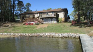 A house with a deck, a small pond, and a stone border.