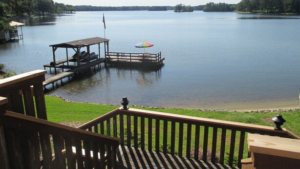 A lakeside deck with a dock, picnic tables, and a flag.