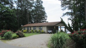 A two-story building with a gravel driveway and a covered parking area.