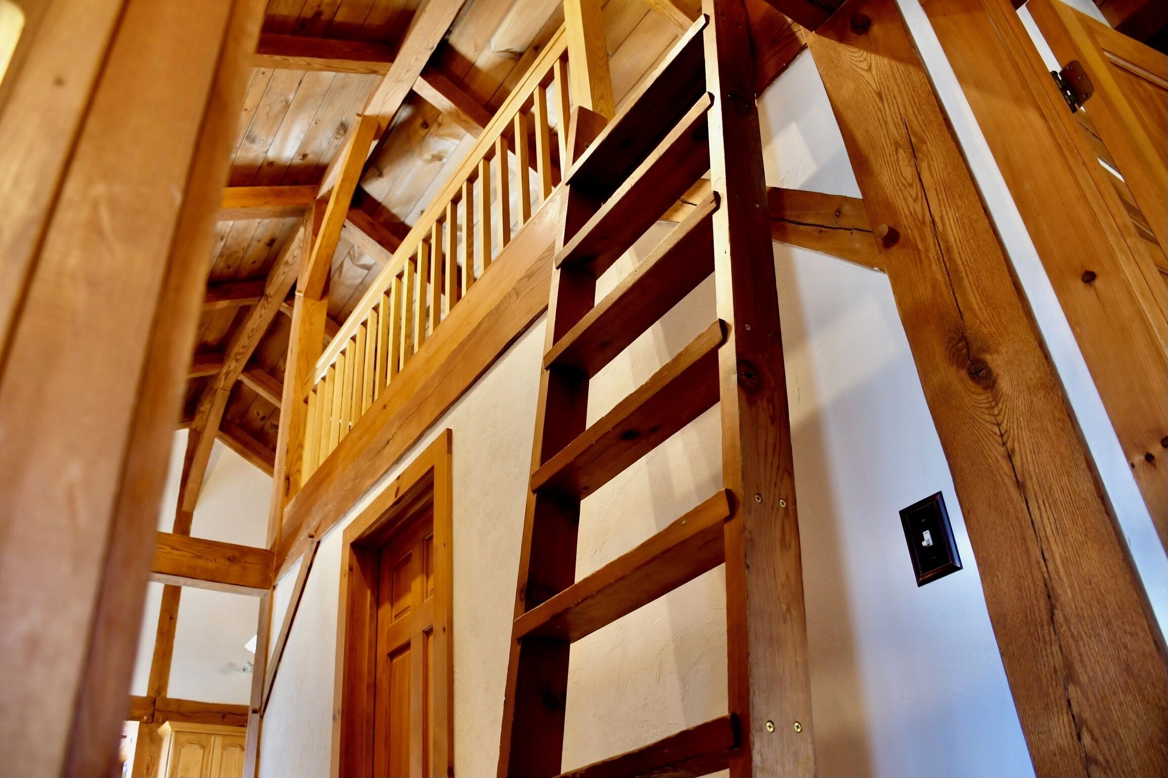 Una escalera de madera que lleva a un balcón con vistas al interior.