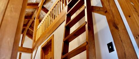A wooden staircase leading to a balcony with a view of the interior.
