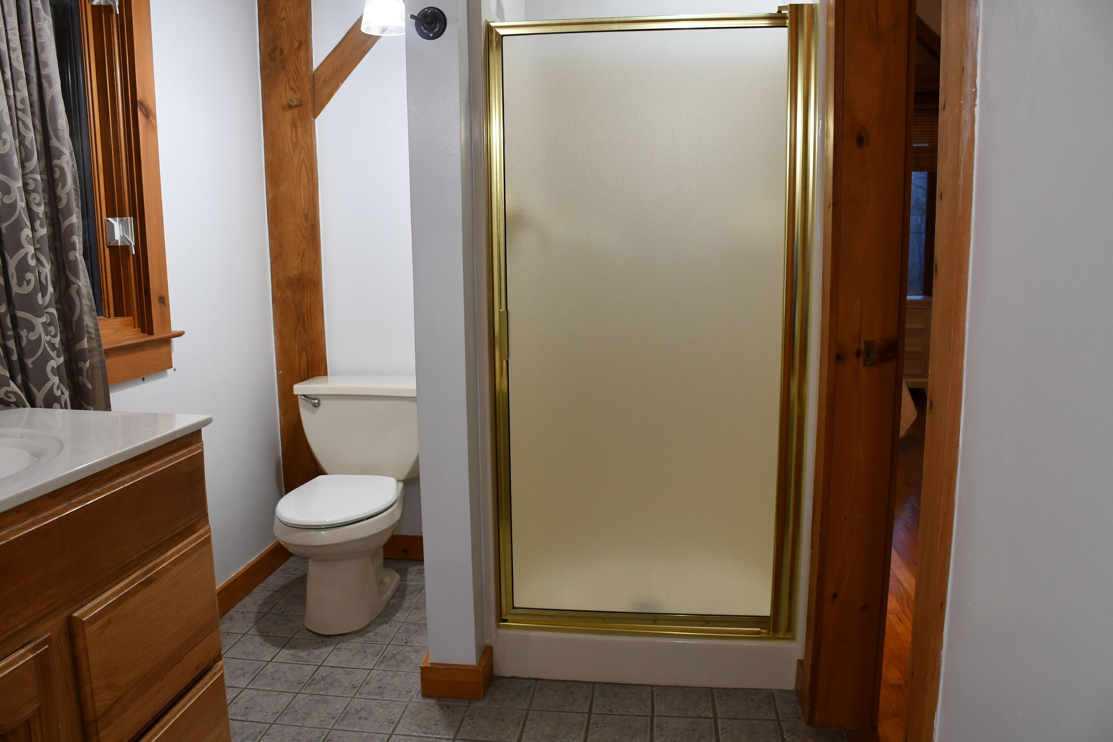 Un baño con inodoro, cabina de ducha y muebles de madera.