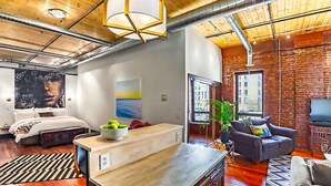 Un salon moderne avec un plafond en bois, une grande fenêtre, un canapé, une table basse et un téléviseur.