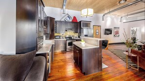 Une cuisine moderne dotée d’appareils électroménagers en acier inoxydable, d’un plancher en bois et d’un îlot central.
