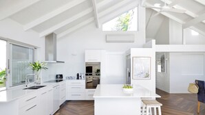 Une cuisine moderne avec des meubles blancs, un îlot central et un parquet en bois disposé en chevrons.