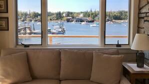 A living room with a large window overlooking a marina with boats and docks. - Upstairs level of two story home (Downstairs is a separate rental) in Bass Hbr. (Bass Harbor)