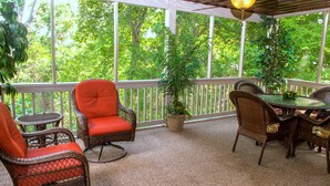 A covered patio with wicker furniture, a table, and potted plants. - Beautiful Home,Pool Table,Ping Pong, Air Hockey, Foosball, Views   250.00 (Massanutten)