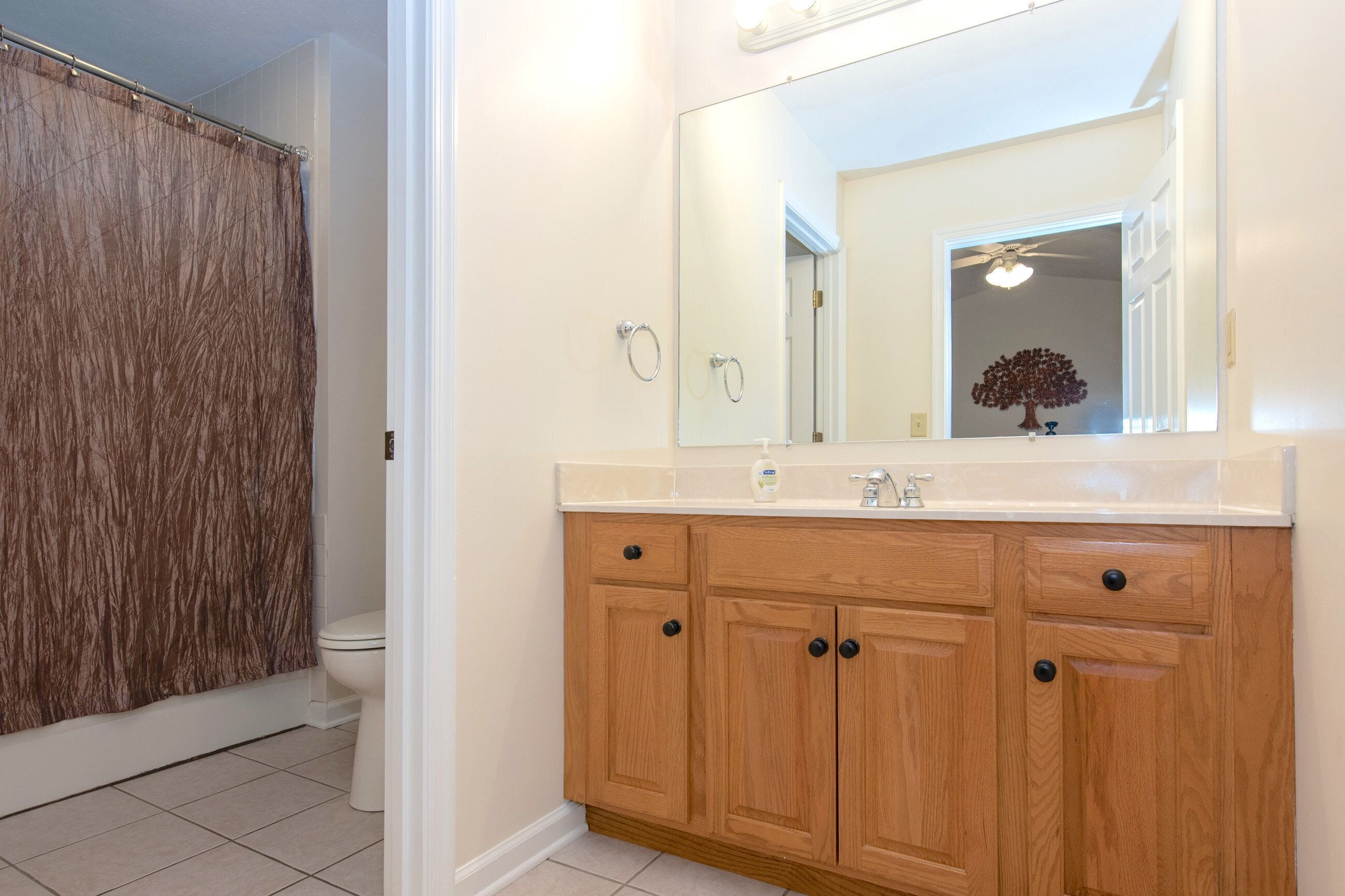 A bathroom with a wooden vanity, a large mirror, and a shower curtain.