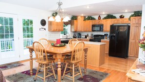 A kitchen with wooden cabinets, a black refrigerator, and a dining area with a wooden table and chairs. - Beautiful Home,Pool Table,Ping Pong, Air Hockey, Foosball, Views   250.00 (Massanutten)