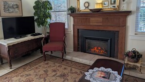A living room with a fireplace, a television, a red armchair, and a large mirror. - Downtown Bungalow! Dog Friendly -  WIFI!   (Brevard)