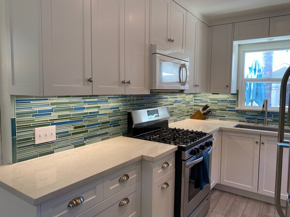 A modern kitchen with white cabinets, a stainless steel stove, and a tiled backsplash.