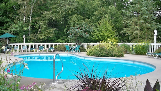 A swimming pool surrounded by greenery and outdoor furniture. - Jackson NH Peaceful, Country Cottage / Access to Fabulous Amenities (Bartlett)