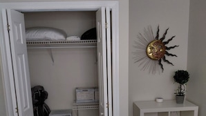 Quarto com cama, guarda-roupa, escrivaninha com abajur e um ornamento na parede.