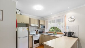 A compact kitchen with a refrigerator, stove, microwave, and sink. - PET FRIENDLY COTTAGES - KELPIE COTTAGE - SELF CONTAINED COTTAGES (Worrolong, Mount Gambier)