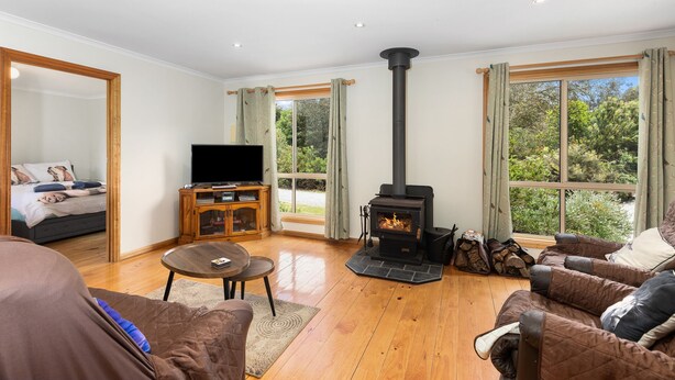 A living room with a fireplace, wooden flooring, a TV, and a sofa. - PET FRIENDLY COTTAGES - KELPIE COTTAGE - SELF CONTAINED COTTAGES (Worrolong, Mount Gambier)