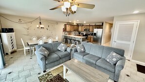 A living room with a grey sectional sofa, a coffee table, and a dining area with a white table and chairs. - BEACH BLOCK, 100 steps to BOARDWALK and SAND, Sleeps 10 (Wildwood)