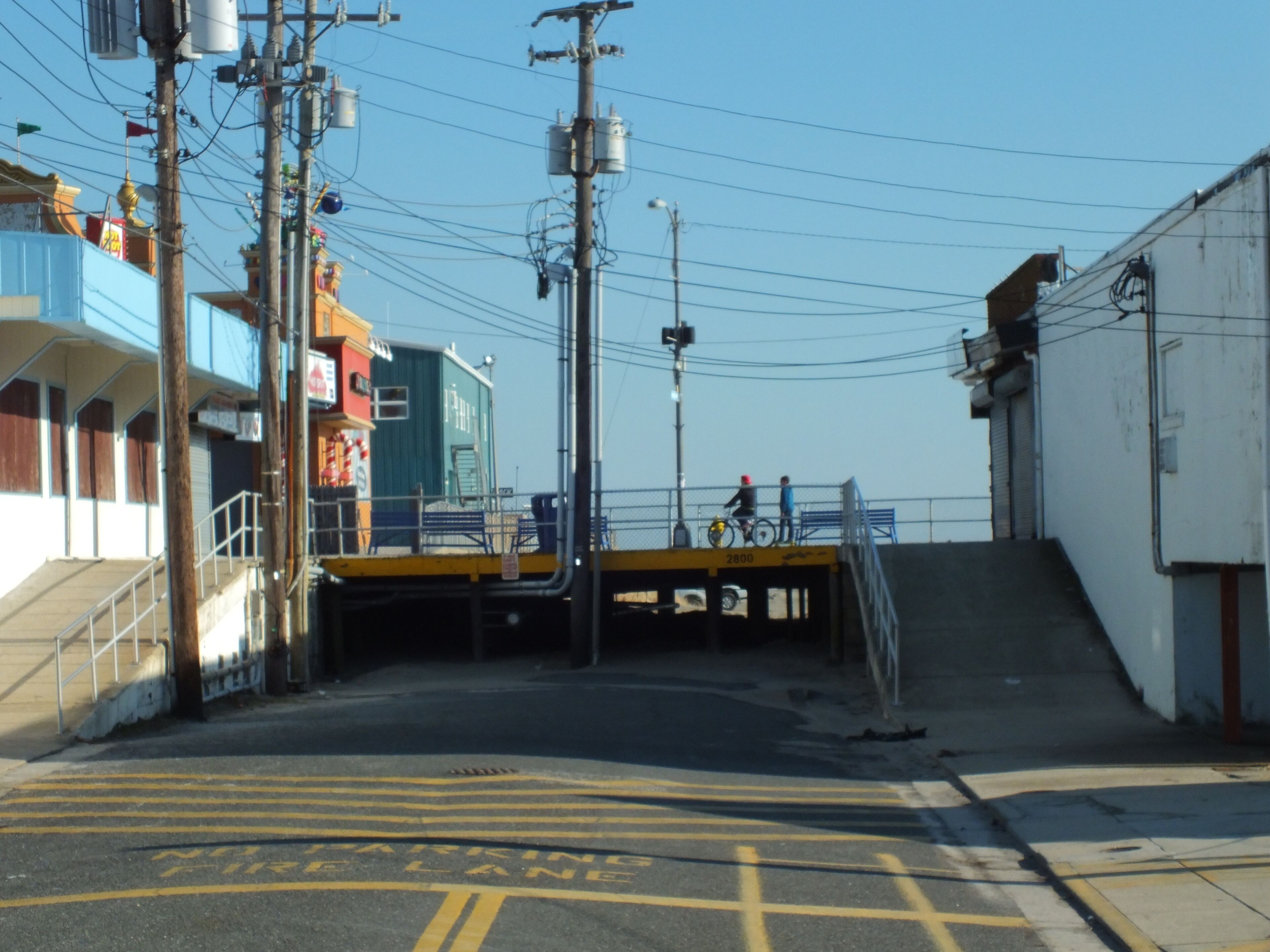 A parking area with yellow lines and a ramp leading to a building.