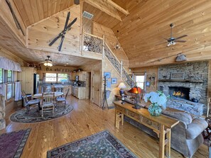 A spacious wooden cabin with a kitchen, dining area, and living room. A staircase leads to an upper level. - River Magic, Romantic Luxury Log Cabin with Hot Tub (Hot Springs)
