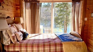 Um quarto aconchegante com colcha xadrez, um edredom e cabeceira de madeira.