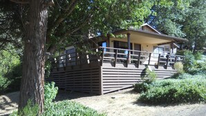 Une cabane en bois dotée d’un balcon, entourée d’arbres et de verdure.